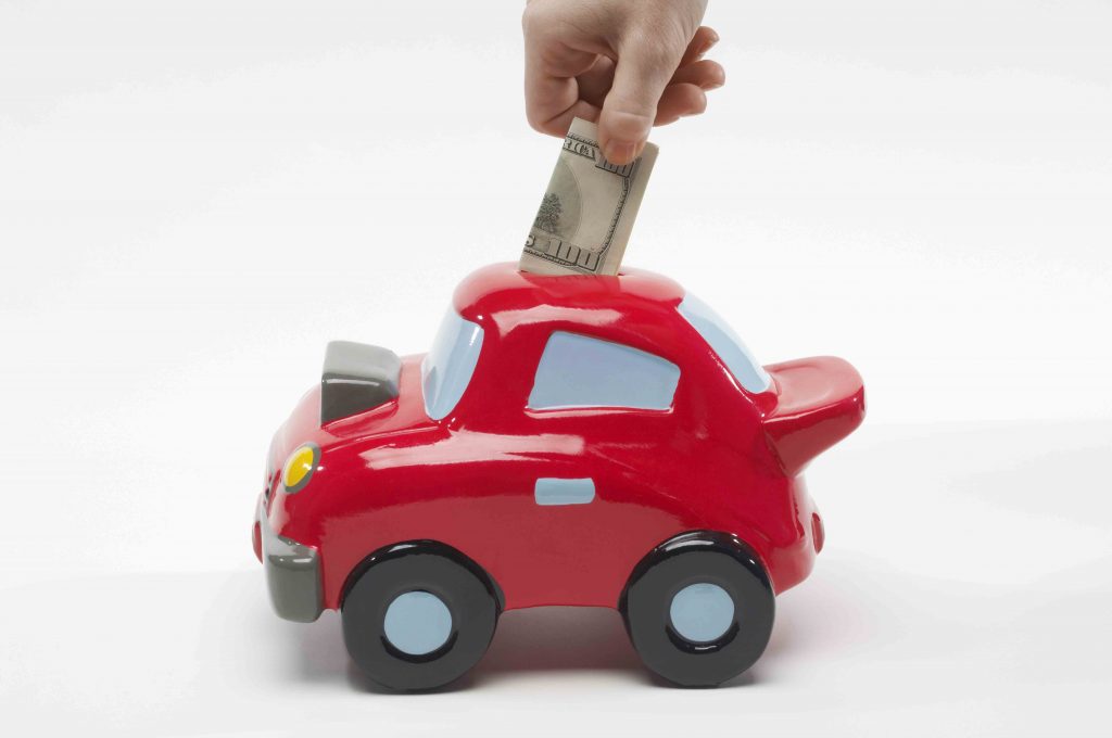 Putting money into car shaped piggy bank - delayed gratification to get what you really want