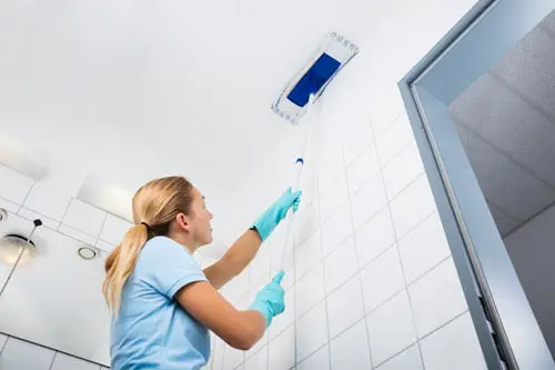 Woman using microfiber mop to clean ceiling