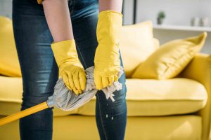 image of woman wearing yellow gloves wringing mop to clean floor