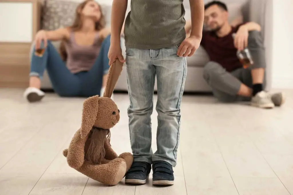 image of a child with their stuffed bunny while parents drink alcohol in the background