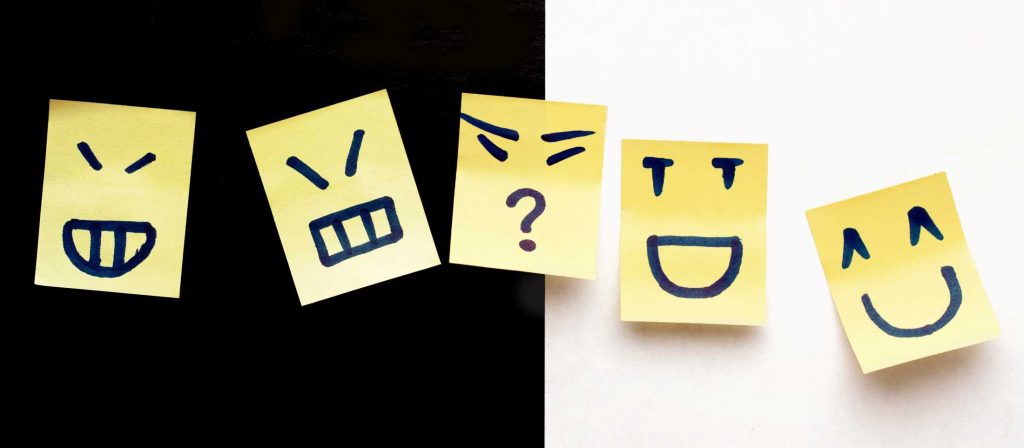 sticky notes depicting different moods - faking happy, neutral, unknown, laughing and smiling