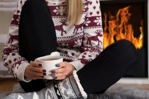 woman drinking coffee in front of fireplace during the holidays