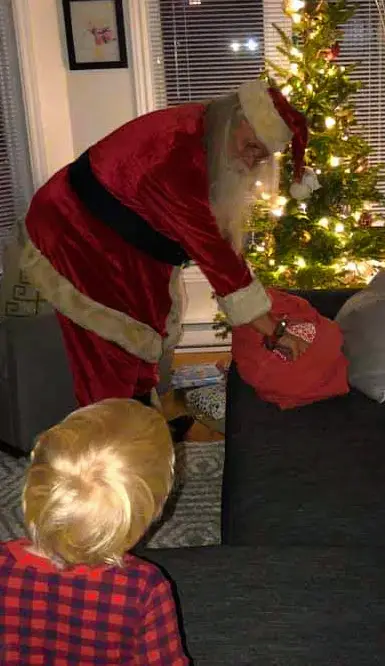 Santa placing little boys presents under tree