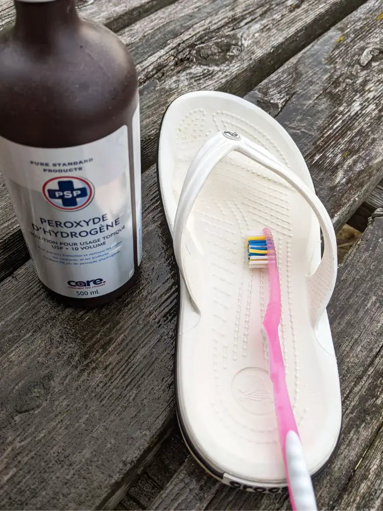 Image shows clean white flip flop on wood deck with a bottle of hydrogen peroxide and toothbrush