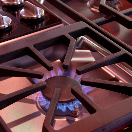 Image of cast iron stove top burner grate with blue flame