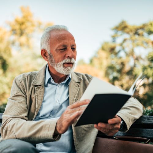 Man reading book on bench
