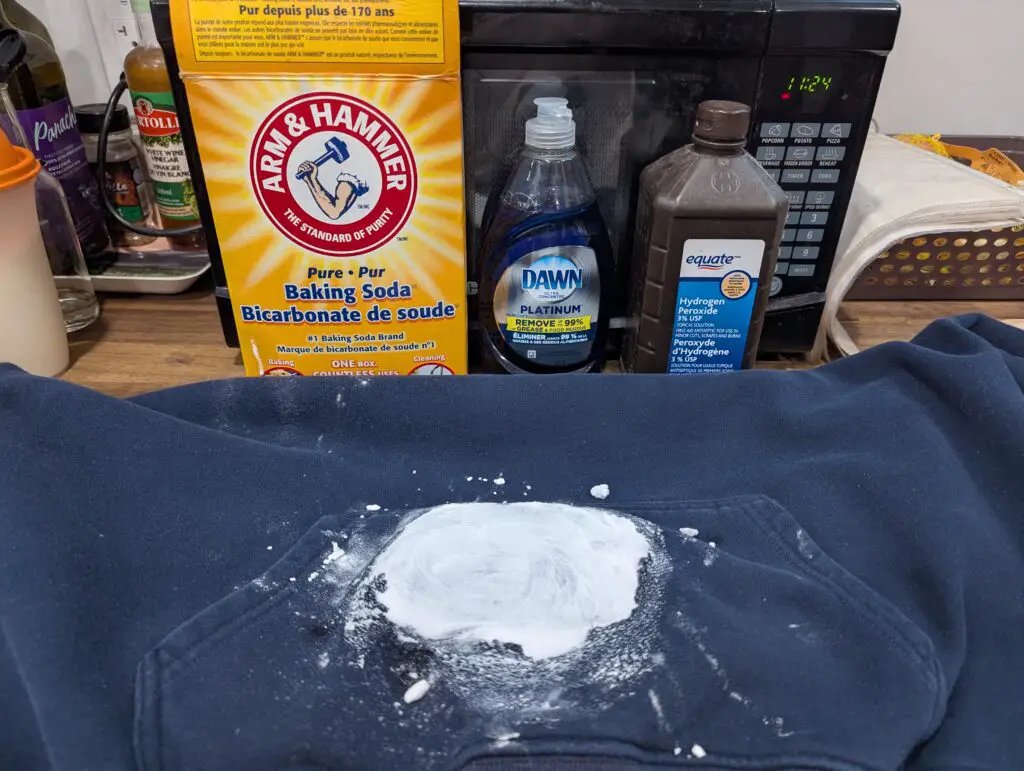 The image showcases a dark garment with a white powder applied to an oil stain, alongside cleaning products labeled for DIY home hacks to effectively remove grease stains from clothes.