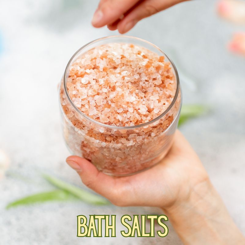 Image of a jar of bath salts held in a hand over a filled bathtub