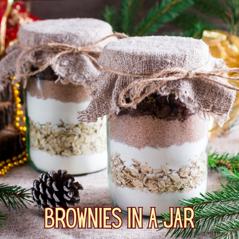 image of 2 jars filled with layers of flour, cocoa, sugar and other ingredients for a homemade Christmas gift. Text reads 'brownies in a jar'