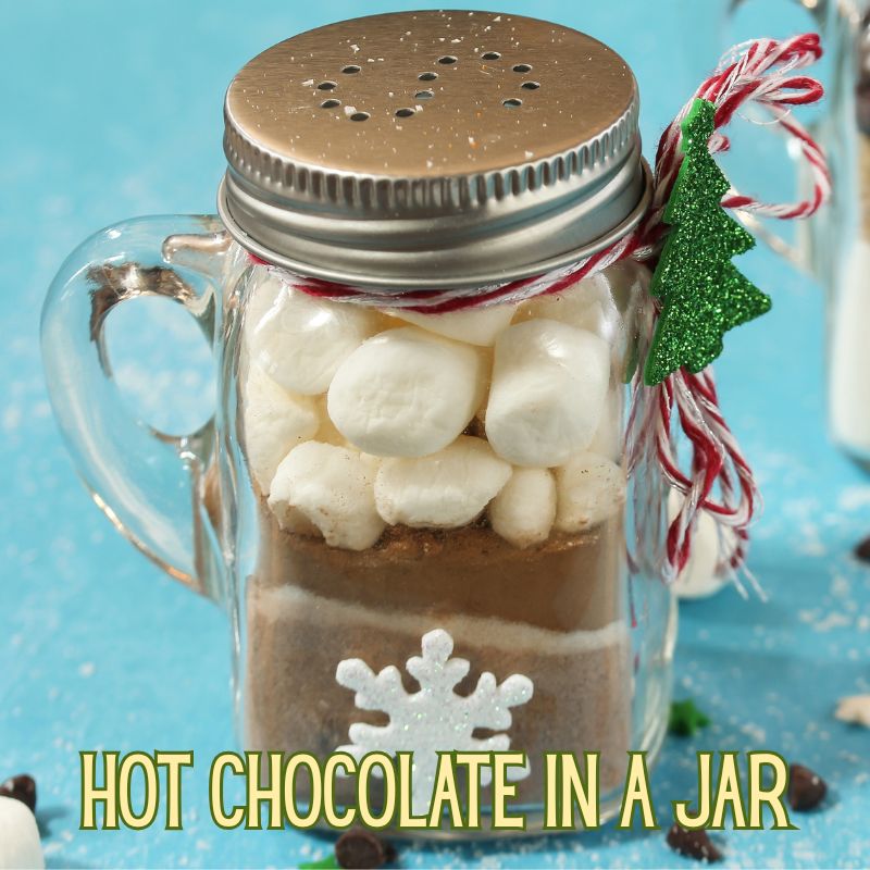 Image of DIY Christmas gift of cocoa, sugar and other hot chocolate ingredients in a mason jar with a handle. Text reads 'hot chocolate in a har'
